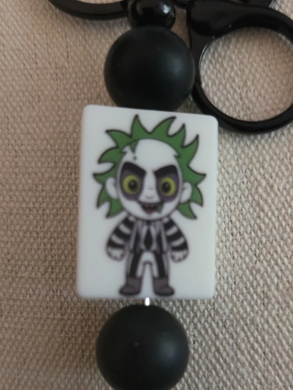 Source Unknown Black and White Character Keychain with Green Accent